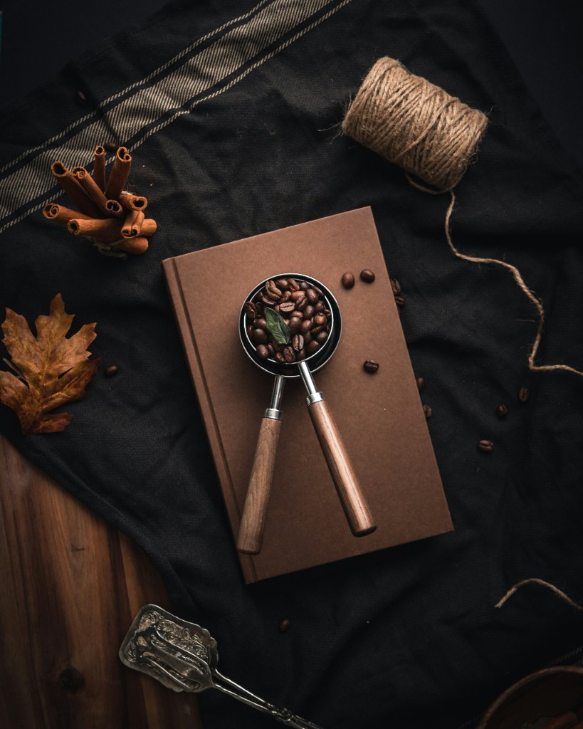 Coffee beans and notebook on a dark surface